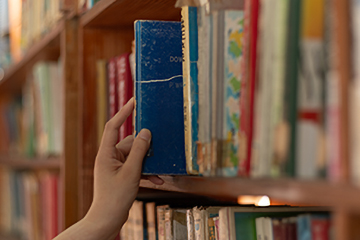 hand removing a book from a library shelf hand removing a book from a library shelf
